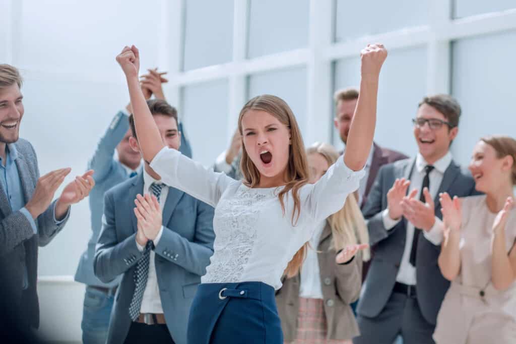 girl with arms up in excitement surrounded by a celebrating people 